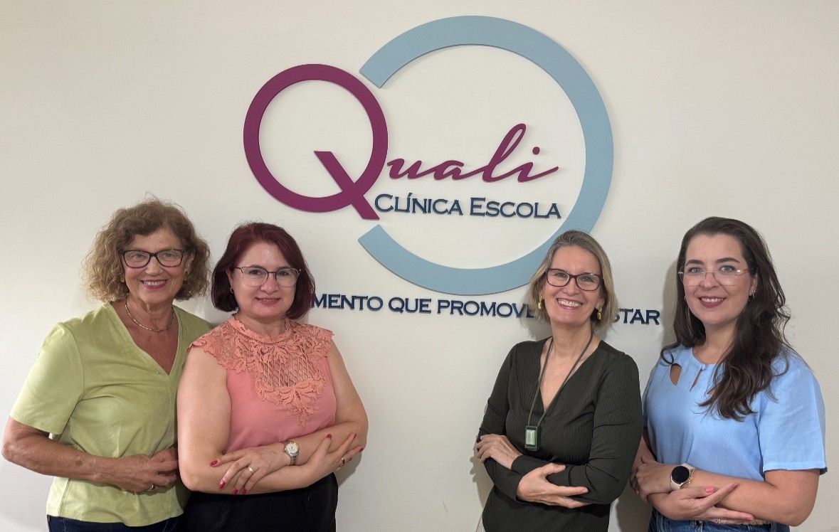 Time da Qualiclínica Escola em frente a logo da clínica